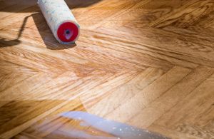 Parquet a spina di pesce con tracce di finitura a vernice e rullo per stenderla