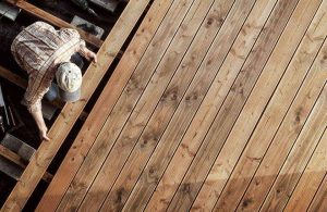 Vista dall'alto su un operaio che sta installando un pavimento in legno di Douglas su una terrazza