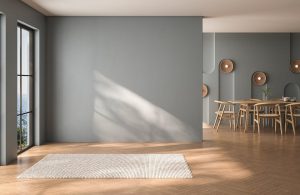Grande ambiente domestico semivuoto in una stanza in cui si intravede il tavolo di una sala da pranzo. Le pareti sono grigie, il soffitto bianco e a terra c'è un parquet a spina di pesce