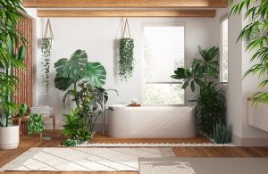 Stanza da bagno d'ispirazione orientale con molte piante, soffitto con travi a vista, piante pensili, grande vasca da bagno bianca, parquet e tappeti