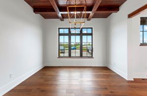 Interno di una stanza vuota di una casa colonica ristrutturata con travi a vista e parquet. C'è una finestra con inferriata che si affaccia su una zona parcheggio