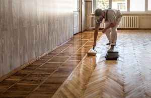 Un operaio sta oliando con un rullo un parquet a spina di pesce