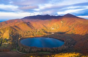 Vista dall'alto di uno dei due laghi di Monticchio, in Basilicata, circondati da montagne e alberi, in autunno