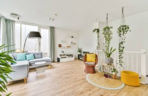 Ampio e luminoso salotto sui toni del bianco, con parquet chiaro piallato, molte piante ed elementi d'arredo con colori accesi