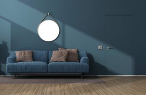 Salotto sui toni del blu scuro, con pareti, porta e sofà dello stesso colore, specchio circolare e parquet