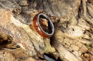 Un braccialetto in legno di cocobolo appoggiato su un pezzo tronco