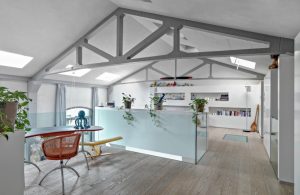 Grande mansarda open space con libreria, scrivania e scale che scendono al piano inferiore