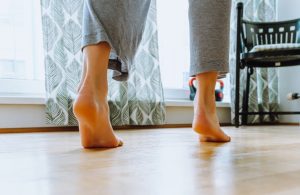 Dettaglio dei piedi scalzi di una donna che cammina su un pavimento in parquet