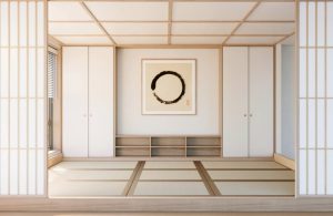 Interno vuoto di una casa tradizionale giapponese con pannelli in legno e carta di riso, pavimenti in legno, tappeti, e un quadro astratto minimale appeso al centro della parete di fondo, sopra a un mobile basso orizzontale, in legno naturale