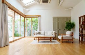 Ampio e luminoso salotto con pavimento in parquet, grande parete vetrata, lucernario, mobili in stile modernista