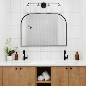 Un mobile da bagno in legno di quercia bianca in una stanza da bagno in stile moderno tutta sui toni del bianco con accenti di nero