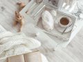 Angolo lettura shabby chic con tavolino bianco, libro e parquet grigio chiaro