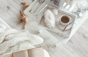 Angolo lettura shabby chic con tavolino bianco, libro e parquet grigio chiaro