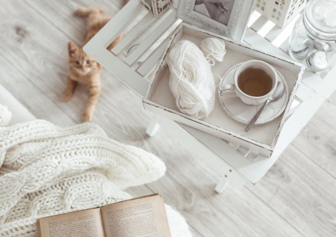 Angolo lettura shabby chic con tavolino bianco, libro e parquet grigio chiaro