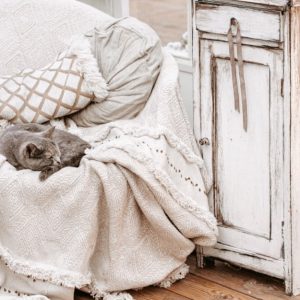 Angolo shabby chic con poltrona in tessuto neutro, mobiletto decapato e parquet rovere sbiancato